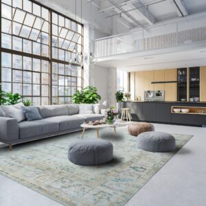 A faded light blue patterned rug anchors a living area in a bright, sunlit industrial loft space.