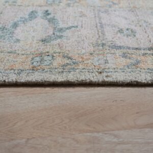 The edge of a textured rug in pale blue, orange, and cream rests on light wood planks.
