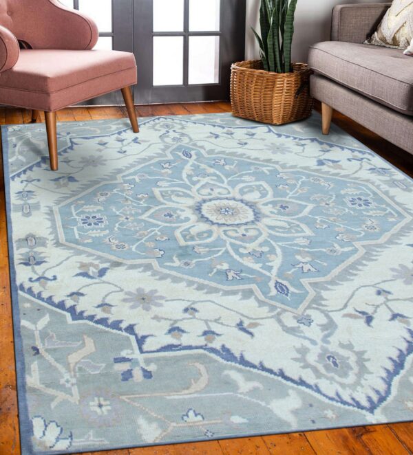 Pale blue traditional medallion rug with cream and dark blue accents in a room with wood floors and chairs.
