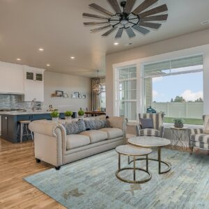 Distressed blue and gray rug covers hardwood floors in an open living room with a beige sofa.