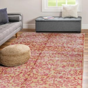 Beige rug with pink floral pattern lies on wood floor between a woven pouf and grey ottoman.