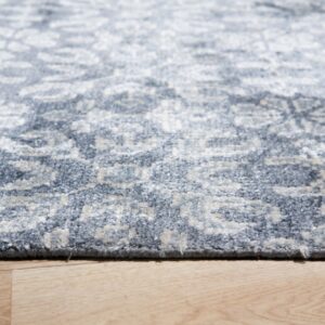 Low-angle view of a textured slate blue and light gray patterned rug lying on light wood planks.