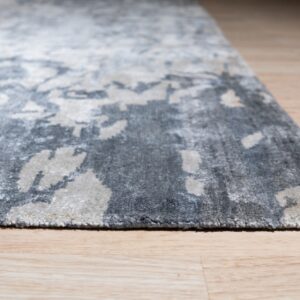 Textured, high-pile gray rug featuring an abstract distressed pattern on light wood plank flooring.