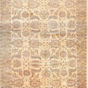Traditional gold and cream rug with an all-over floral and vine pattern and fringed edges.