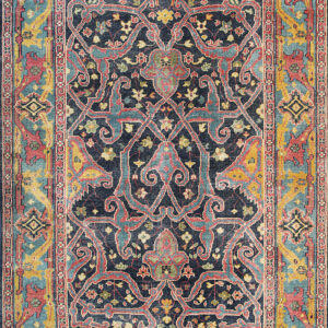 Low-pile area rug displaying a complex floral medallion pattern in navy, pink, teal, and mustard yellow.