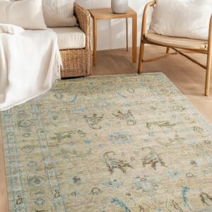 Beige and pale blue traditional rug defines a bright seating area with wicker furniture on wood flooring.