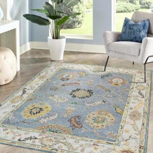 Traditional blue and gold area rug featuring an ornate border placed beneath a gray upholstered chair.
