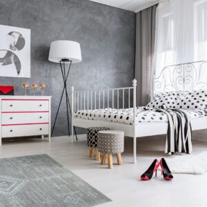 A gray, low-pile rug with a light geometric pattern sits on a light floor in a modern bedroom.