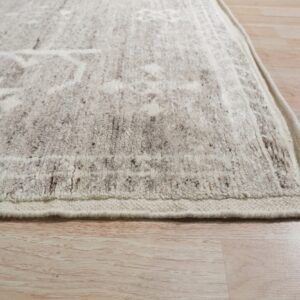 Textured cream and brown patterned rug edge shown close-up on light wood plank flooring.