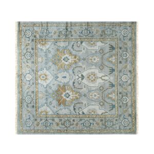 Low-pile square rug with traditional gold, teal, and cream motifs on a light blue background.