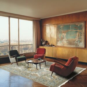 A living room with wood floors features a traditional gray and gold rug under mid-century chairs.