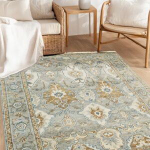 A distressed gray and tan traditional patterned rug anchors rattan and wicker furniture on light wooden flooring.