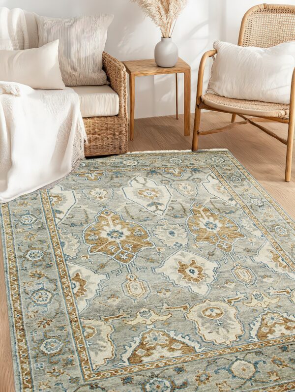 A distressed gray and tan traditional patterned rug anchors rattan and wicker furniture on light wooden flooring.