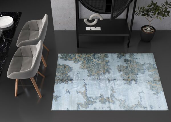 Lustrous, distressed blue and taupe rug anchors a minimalist room with gray chairs and concrete walls.