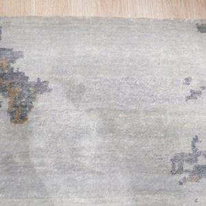 Light gray rug with abstract blue and tan pattern accents visible on light wood flooring.