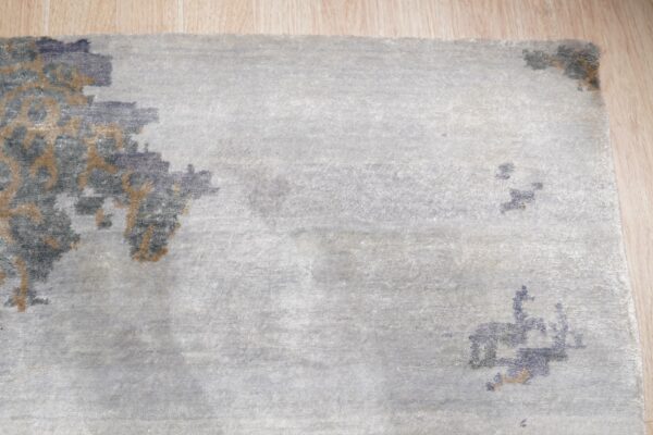 Light gray rug with abstract blue and tan pattern accents visible on light wood flooring.