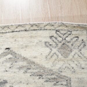 Textured high-pile cream rug with an abstract gray pattern rests on light wood planks.