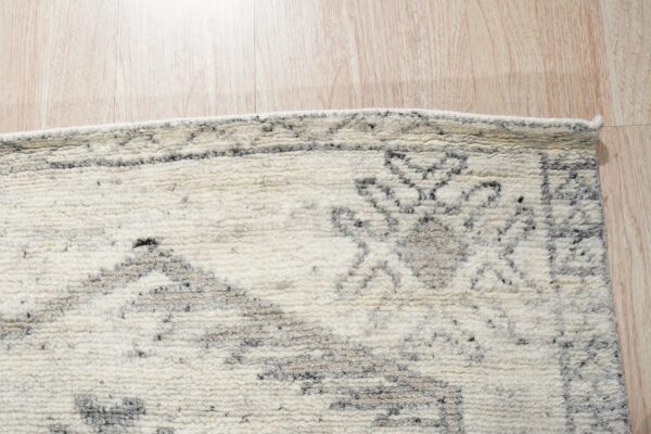 Textured high-pile cream rug with an abstract gray pattern rests on light wood planks.