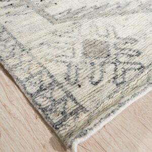 Textured high-pile rug in off-white with dark gray geometric patterns resting on light plank flooring.