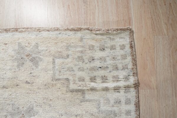High-pile ivory rug with a chunky taupe geometric pattern lies on light wood flooring.