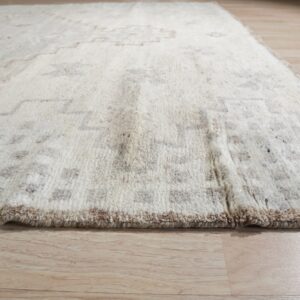 High-pile cream rug with geometric brown and gray patterns sits on light wooden flooring.