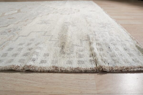High-pile cream rug with geometric brown and gray patterns sits on light wooden flooring.