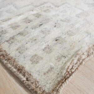 Shaggy cream and brown speckled rug with a subtle geometric pattern rests on light wood plank flooring.