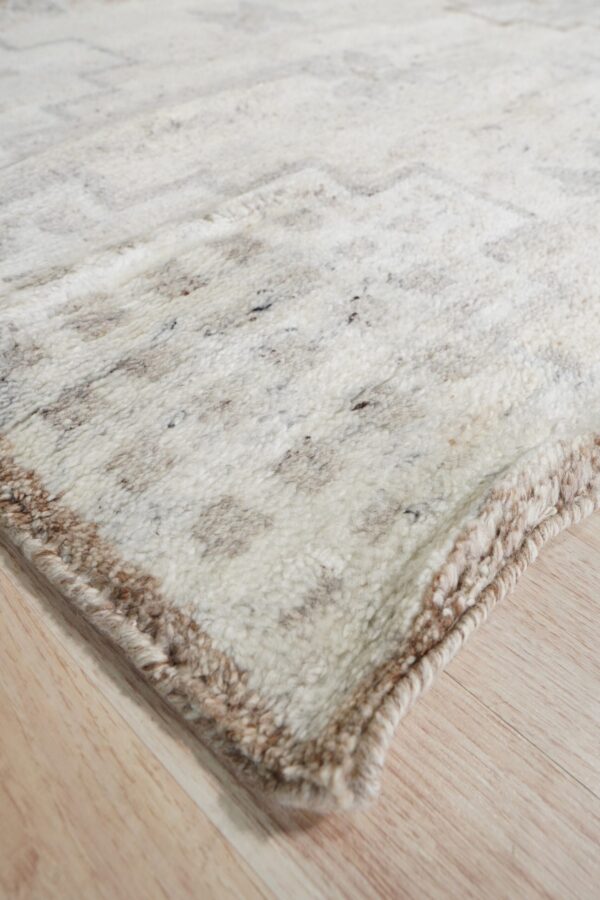Shaggy cream and brown speckled rug with a subtle geometric pattern rests on light wood plank flooring.