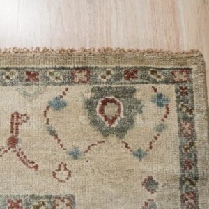 Textured high-pile rug detail showing cream, rust, and slate blue traditional designs on light wood floor.