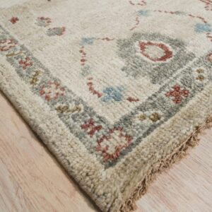 High-pile cream and beige rug with patterned blue, gray, and rust borders on light wood flooring.