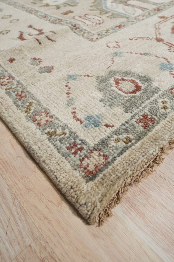 High-pile cream and beige rug with patterned blue, gray, and rust borders on light wood flooring.