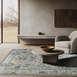 Dusty light blue and sage traditional rug anchors a modern living space with wood flooring and natural light.