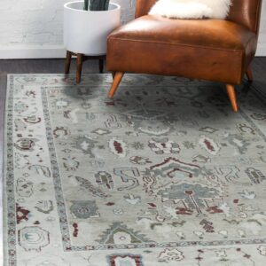A pale gray patterned rug sits under a brown leather chair next to a potted plant.