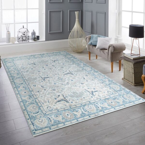 Light blue, gray, and white traditional rug on gray wood flooring next to a cushioned bench.