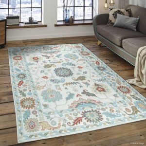 White and light blue low-pile rug with traditional patterns covers distressed wood floors in a sunlit room.