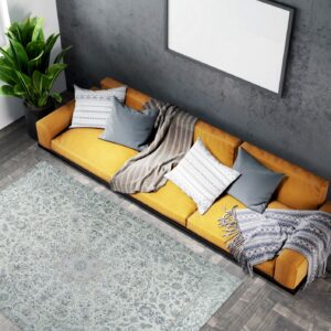 Traditional gray-blue rug anchors a room with dark herringbone floors and a bright yellow couch.