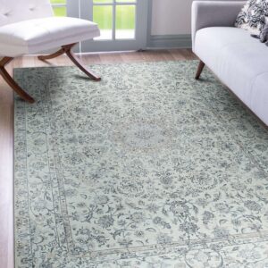 Pale blue-gray traditional medallion rug on wood floors near a white chair and a glass patio door.