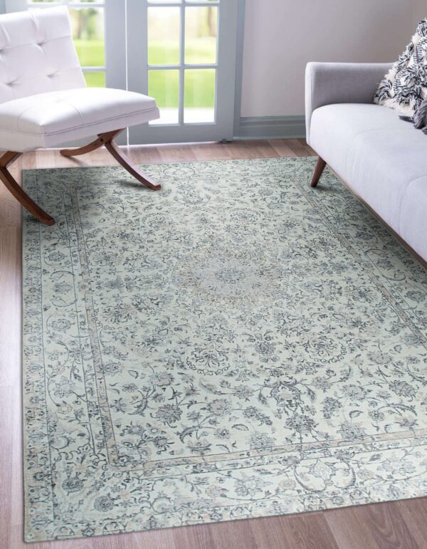 Pale blue-gray traditional medallion rug on wood floors near a white chair and a glass patio door.