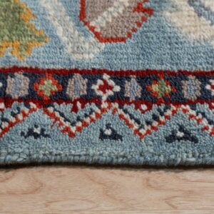 A textured blue rug close-up displays geometric red, navy, green, and yellow patterns on light wood floor.