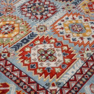 Close-up of a medium pile rug featuring a colorful geometric pattern on a light blue background.