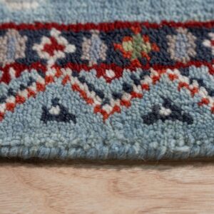 Detail of a medium-pile rug featuring blue, red, and navy geometric patterns on a light wooden surface.