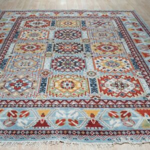 Blue rug featuring a multicolored geometric pattern of square medallions and visible fringes on wood flooring.