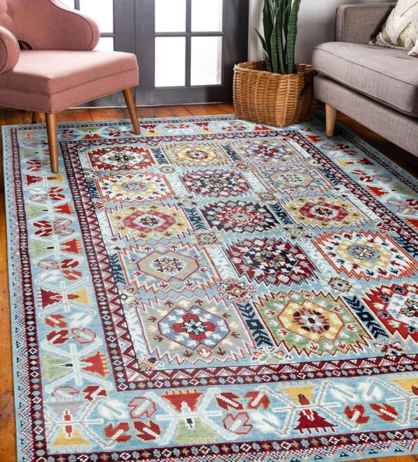 Light blue geometric rug with red, yellow, and navy details rests beneath a pink chair and gray sofa.