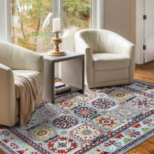 A light blue geometric rug with red and yellow accents sits between two curved white chairs on hardwood floors.