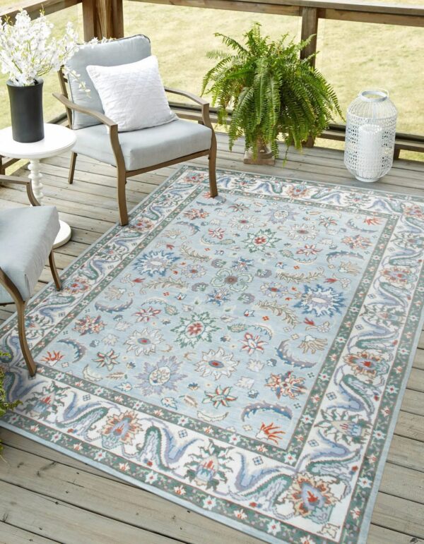 Outdoor light blue rug with a floral pattern rests beneath two cushioned patio chairs.