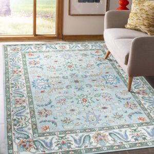 Light blue low-pile rug with colorful floral motifs next to a gray armchair by a window.