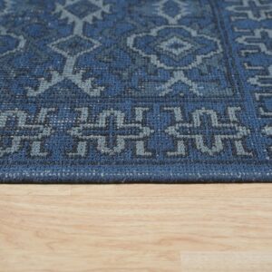 Close-up of a textured dark blue rug with light blue geometric patterns on wood flooring.