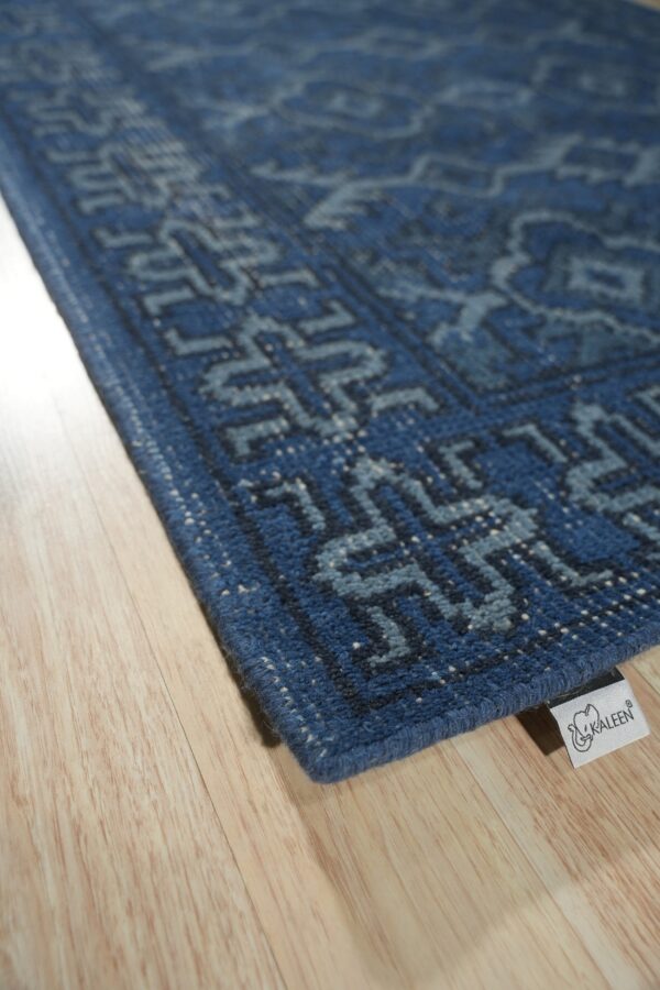 Angled view of a low-pile blue rug featuring light geometric patterns on light wooden floor planks.