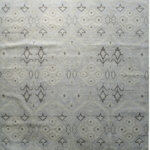A muted blue-gray rug with repeating stylized floral and geometric motifs in taupe and light beige.