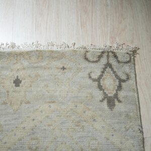Textured cream rug featuring subtle beige and charcoal geometric patterns shown on light wood planks.